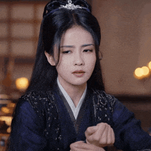 a woman with a tiara on her head is wearing a blue kimono