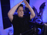 a man in a black shirt holds his hands up in the air