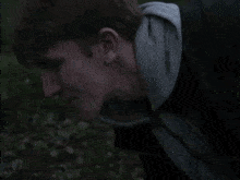 a man in a hoodie is standing in a field looking at something .