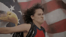 a woman is standing in front of an american flag with a bald eagle on it .