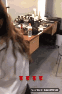 a woman is standing in front of a messy desk with three red roses on her back