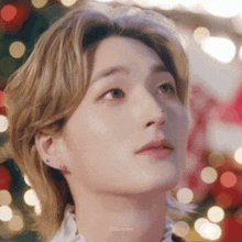 a close up of a man 's face with a christmas tree in the background .