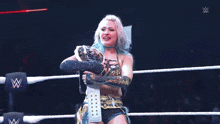 a woman in a wrestling ring is holding a trophy