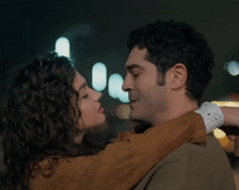 a man and a woman are hugging and looking at each other