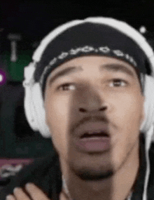 a man wearing headphones and a bandana is making a face .