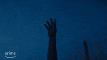 a person 's hand is reaching up into the night sky with a prime logo behind them