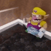 a stuffed animal of wario is sitting in a bathtub holding a book .
