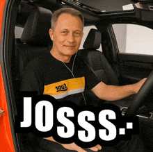 a man wearing headphones is sitting in the driver 's seat of a car with the words josss- written in white