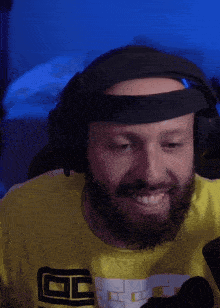 a man with a beard wearing headphones and a yellow shirt with the letter g on the front