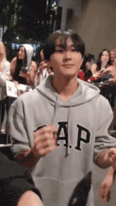 a man wearing a gap hoodie stands in a crowd of people