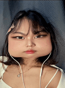 a woman wearing headphones and a white top has a huge face