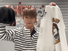a man in a striped shirt is holding a sweatshirt that says emotionally unanswerable
