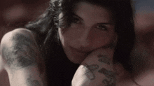 a woman with a lot of tattoos on her arms is smiling