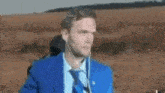 a man in a blue suit and tie is wearing earbuds .