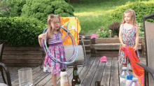 two little girls are playing with hula hoops on a deck