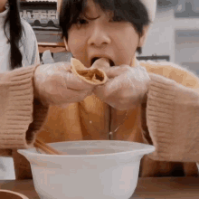 a person wearing plastic gloves is eating a tortilla