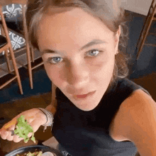 a young woman is sitting at a table eating a salad .