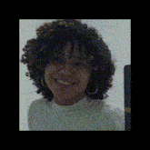 a woman with curly hair is smiling and taking a selfie with her phone .