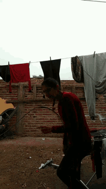 a woman in a red shirt is standing in front of a clothes line