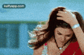 a woman in a red saree is holding her hair in her hand .