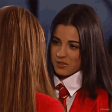 two girls are looking at each other and one has a red tie