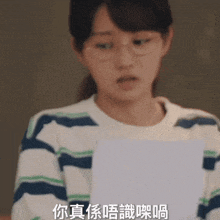 a woman wearing glasses is holding a piece of paper with chinese writing on it