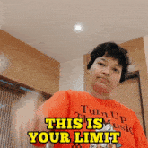 a man wearing an orange shirt that says turn up music