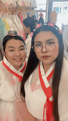 a woman wearing glasses stands next to another woman wearing a headband with flowers in it