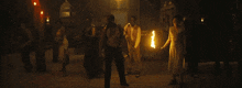 a group of people are standing in a dark room holding fire torches .