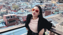 a woman wearing sunglasses stands in front of a cityscape