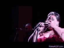a woman singing into a microphone with makeagif.com written on the bottom