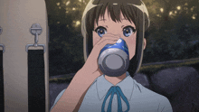 a girl drinking from a blue cup with the letter o on the top