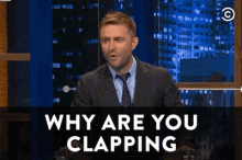 a man in a suit and tie says " why are you clapping " on the screen