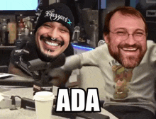 a man wearing a beanie with the word blizzard on it smiles next to another man