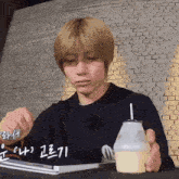 a man sitting at a table with a cup of milk and a fork in front of a brick wall