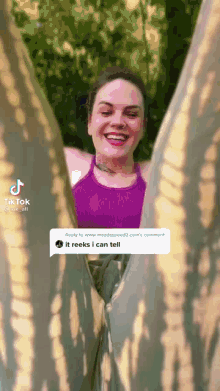 a woman in a purple tank top and tie dye pants is smiling and looking through a hole in a blanket .