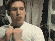 a man in a white shirt is tying his tie .