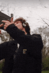 a man wearing headphones and a carhartt jacket is pointing