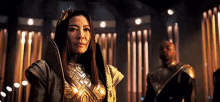 a woman in a gold costume is standing next to a man in a black uniform in a dark room .