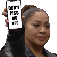 a woman holds up a cell phone that says " don 't piss me off "