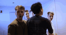 a group of young men standing in a room with a blue light on the ceiling