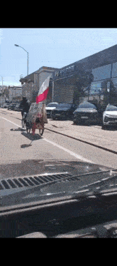 a person riding a bike down a street in front of a hyundai store