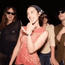 a woman is dancing with a group of people at a party while wearing sunglasses .