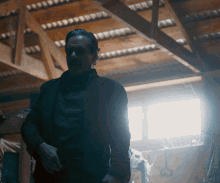 a man is standing in a dark room with a light shining through the ceiling