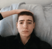 a man laying on a bed with his hand on his head