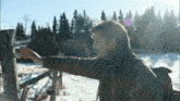a man with a backpack reaches for a wooden post in the snow