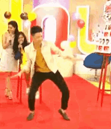 a man is dancing on a red carpet in front of a sign that says coca cola .