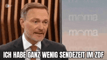 a man with a beard is wearing a suit and tie and talking on a television show .