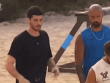 three men are standing next to each other on a beach .