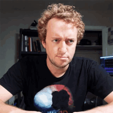 a man wearing a black t-shirt with the word war on it looks at the camera